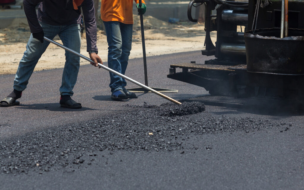 Worker repairing paving on asphalt road