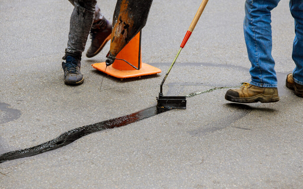 Workers creacksealing on asphalt lot