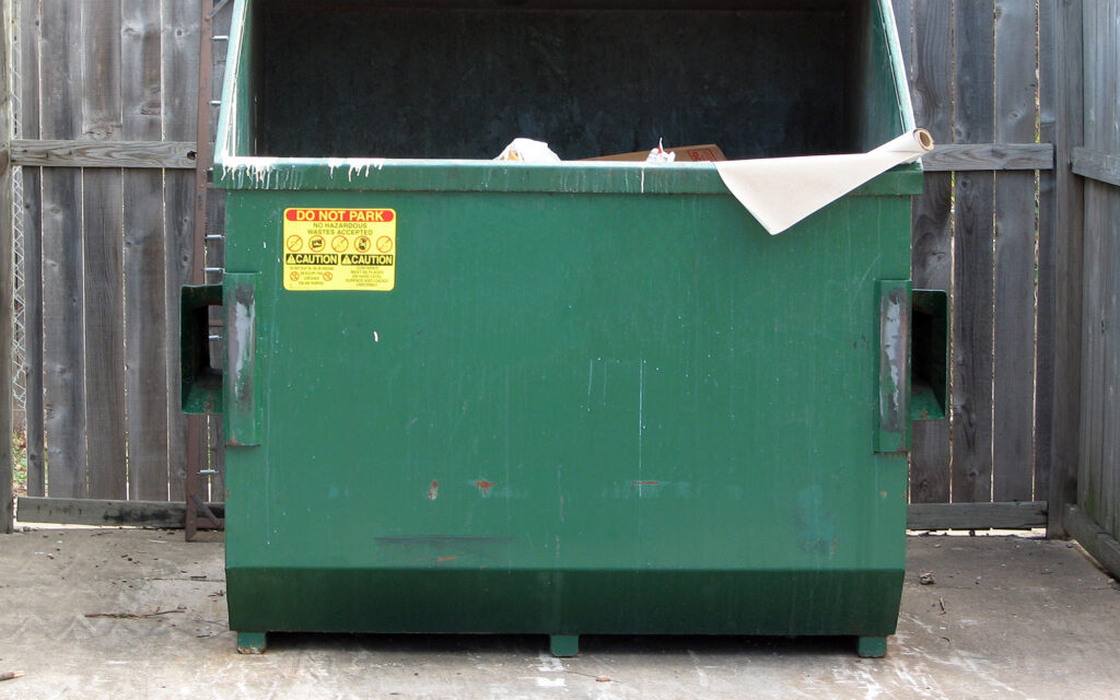 Green dumpster on concrete dumpster pad